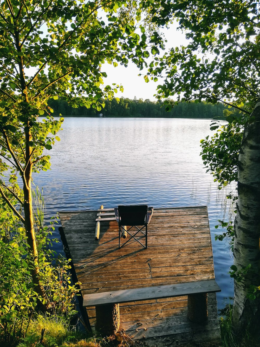 a chair sitting on a dock next to a body of water