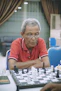 Photo of a middle-aged man analyzing a chessboard with intense focus in a cozy room.
