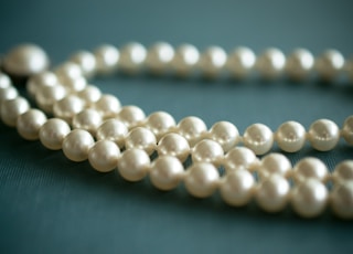 white pearl necklace on gray textile