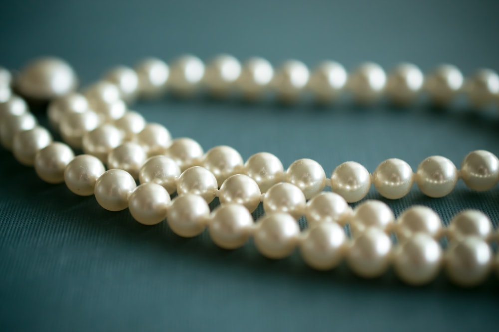 white pearl necklace on gray textile