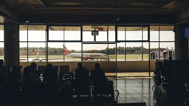 A sleek modern shuttle van waiting at Soekarno-Hatta airport terminal with passengers boarding.
