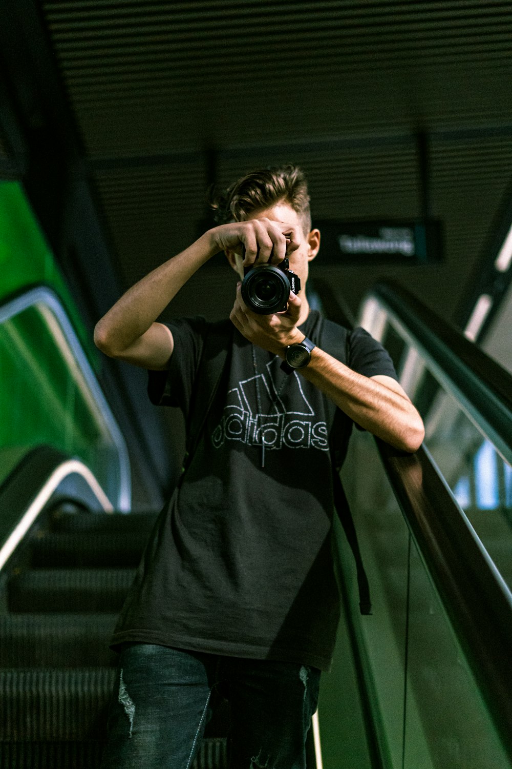 homme en noir ras du cou T-shirt tenant un appareil photo reflex numérique noir