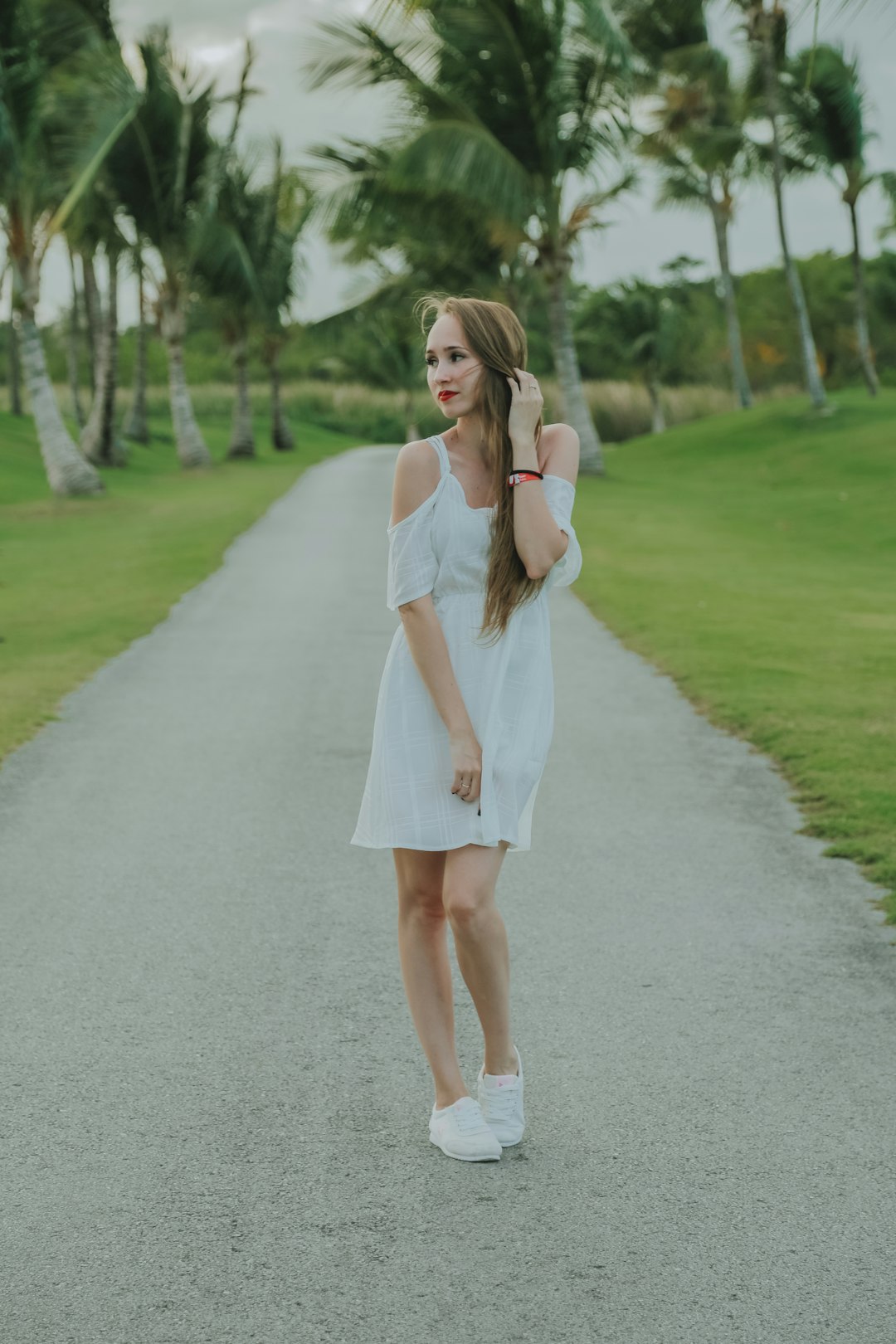 woman in white dress standing on gray asphalt road during daytime