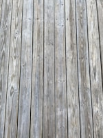 Weathered wooden planks arranged in parallel lines with visible grain patterns and small knots.