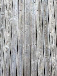 Weathered wooden planks arranged in parallel lines with visible grain patterns and small knots.