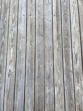 Weathered wooden planks arranged in parallel lines with visible grain patterns and small knots.