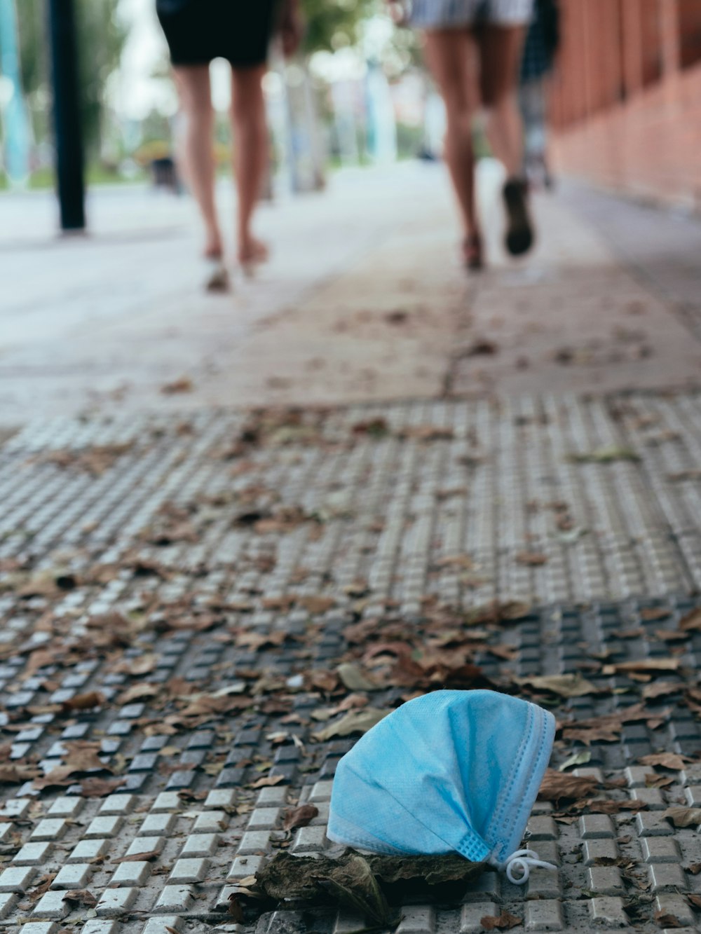 Persona en jeans de mezclilla azul caminando sobre piso de ladrillo marrón durante el día