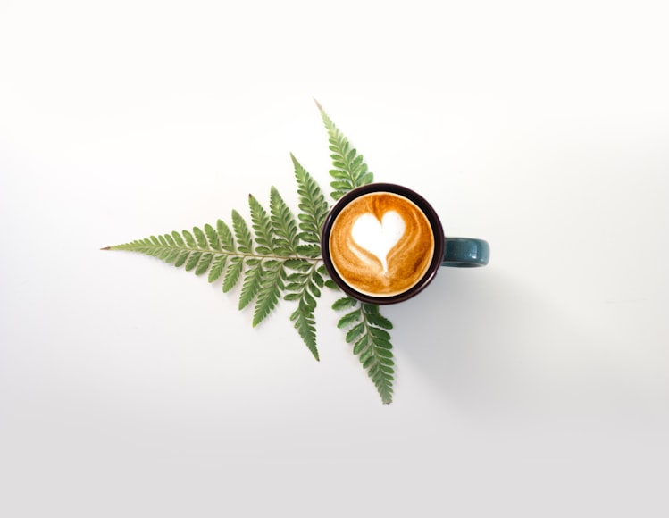 A cup of coffee with green leaves in the background