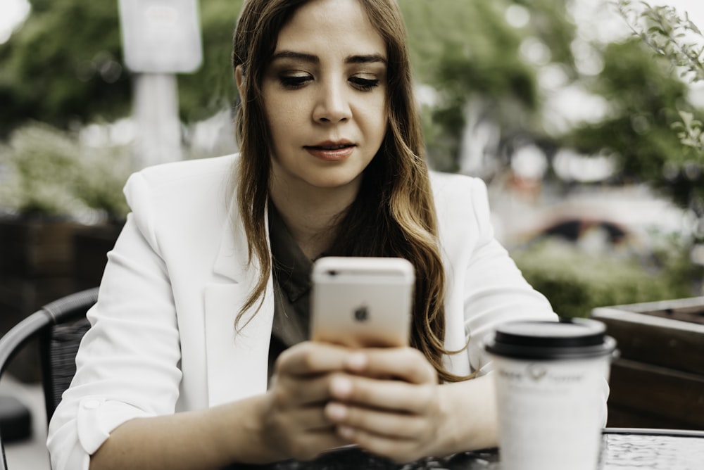 Mujer en blazer blanco sosteniendo un teléfono inteligente Samsung Android blanco