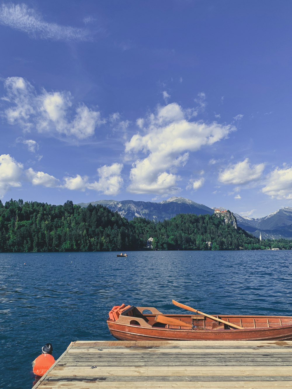 brown boat on body of water near green trees under blue sky during daytime