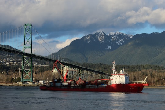 red and white boat on body of water near bridge during daytime in Lions Gate Bridge Canada