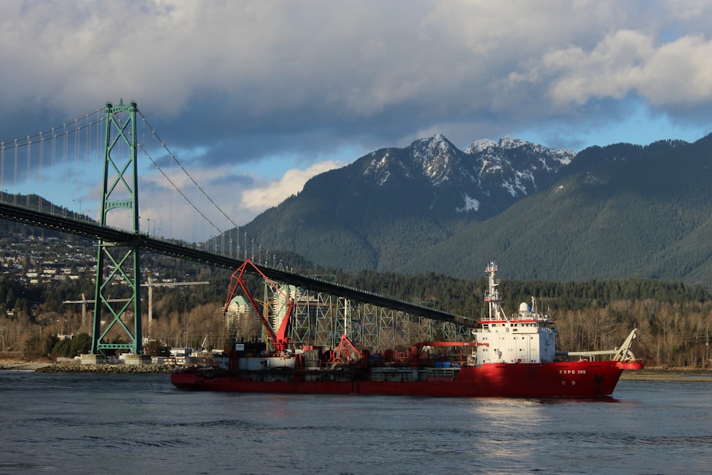 red and white boat on body of water near bridge during daytime