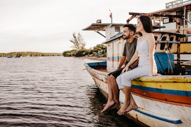 photography poses for couples,how to photograph woman in white and blue striped dress sitting on white and blue boat during daytime