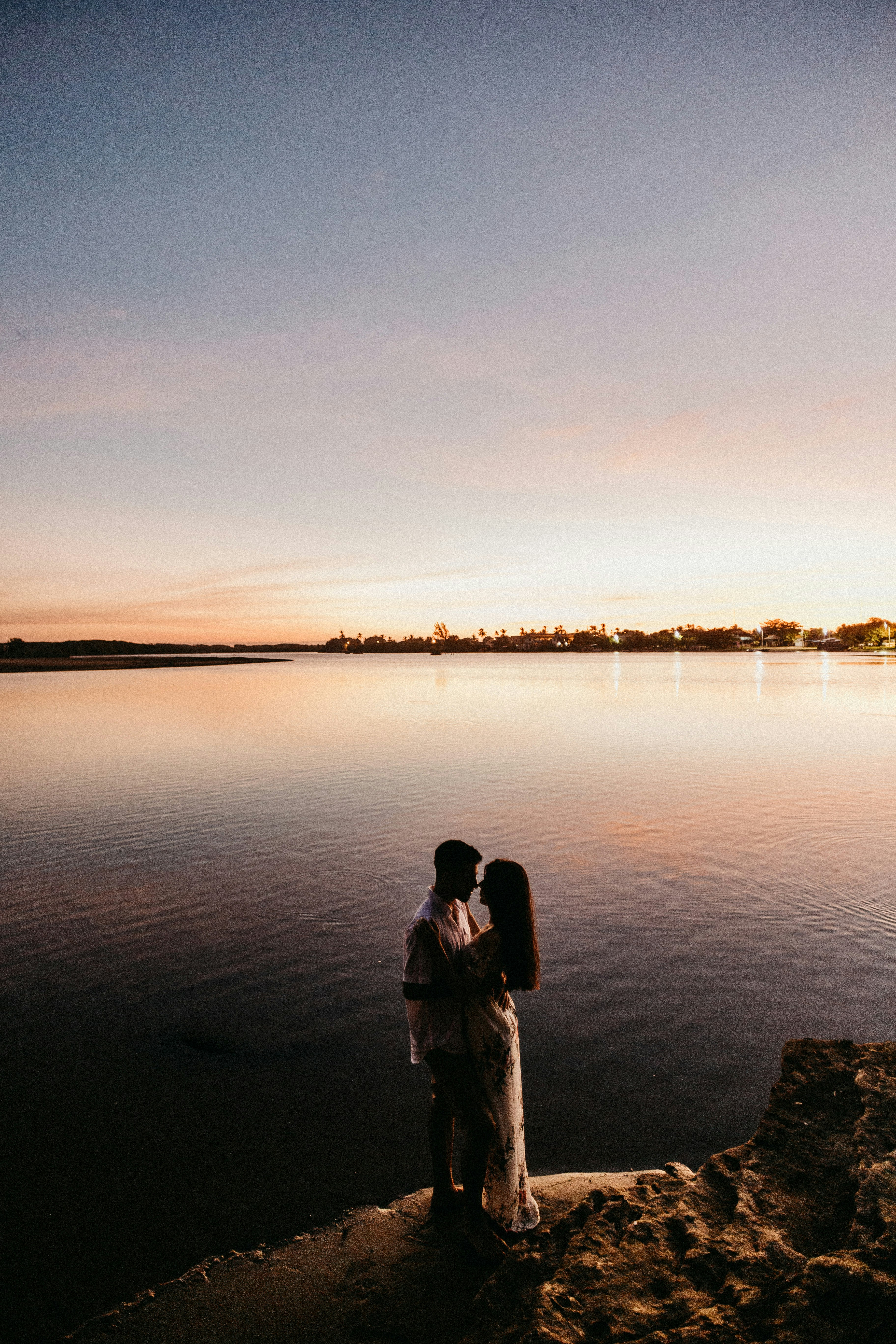 man in black jacket standing on water during sunset