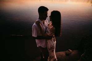 Couple enjoying a romantic moment by the riverbank at sunset