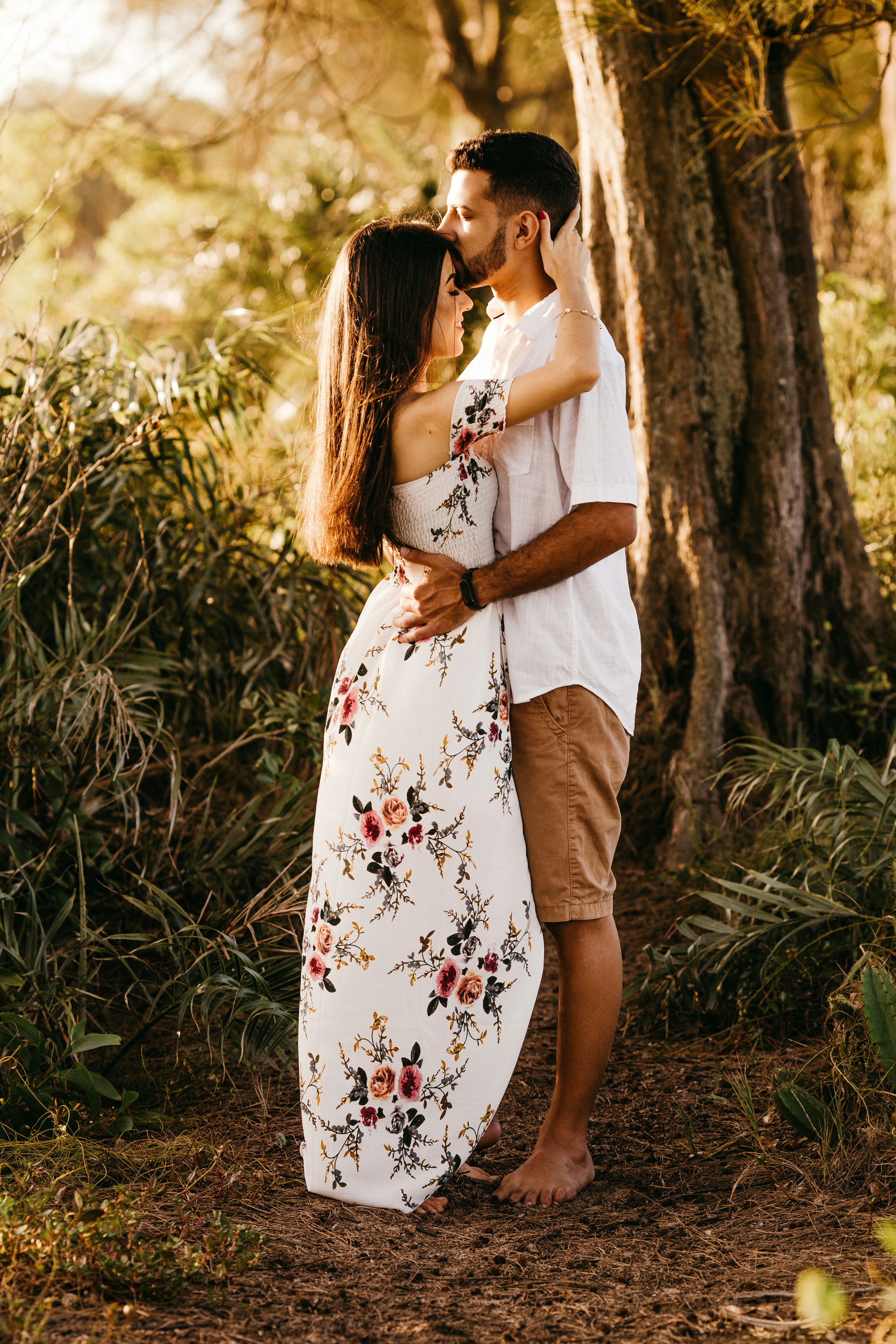 woman in white floral dress standing near tree