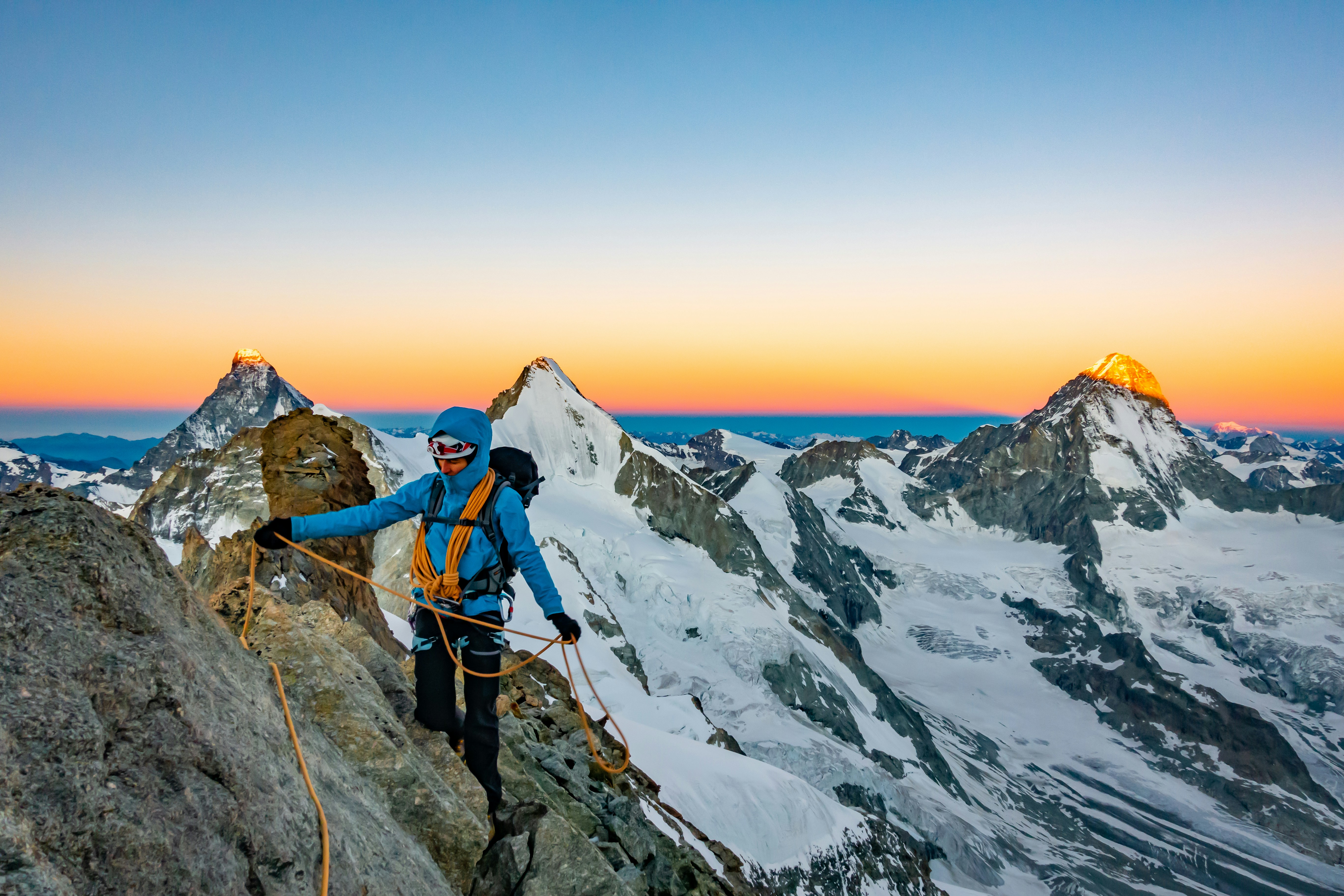 man in blue jacket and black pants standing on rock formation during daytime, Sunrise over Matterhorn, Obergabelhorn and Dent Blanche. One more magic morning on the beautiful 