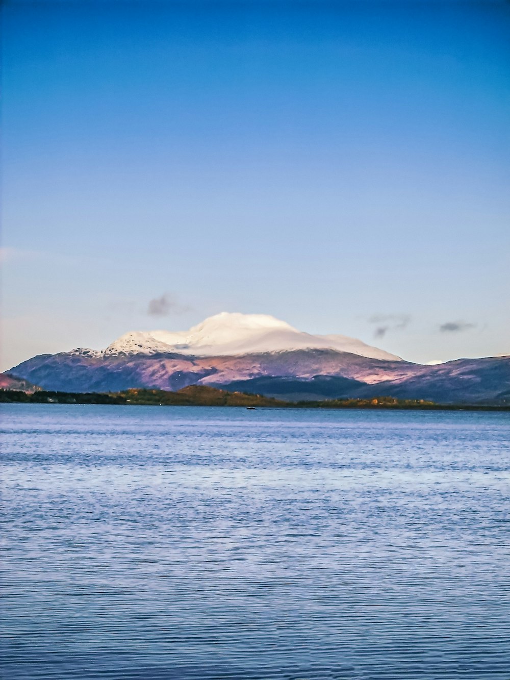 body of water near mountain under blue sky during daytime