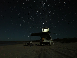 white and black camping chair on brown sand during night time