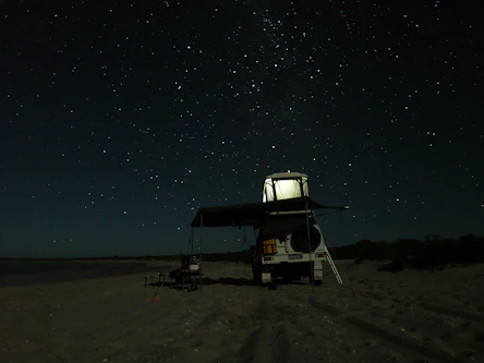 white and black camping chair on brown sand during night time