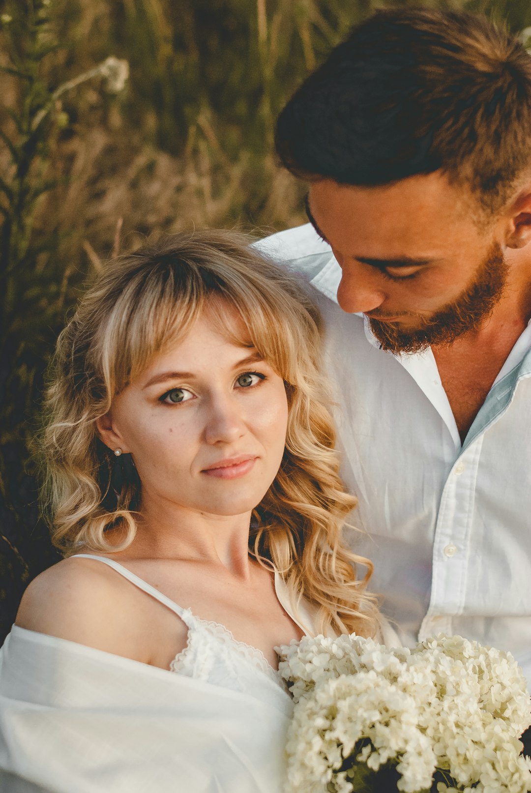 man in white dress shirt kissing woman in white sleeveless dress