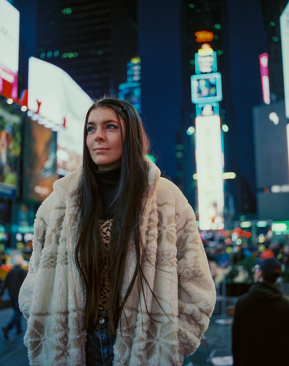 woman in brown fur coat standing near people walking on street during daytime