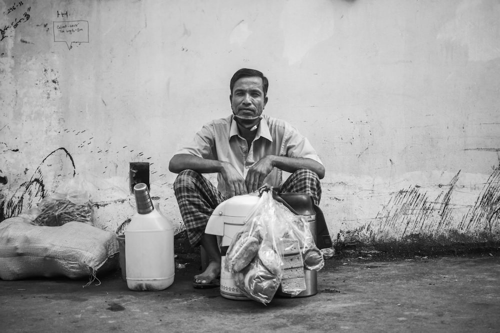 man in black and white stripe dress shirt sitting beside white plastic bags