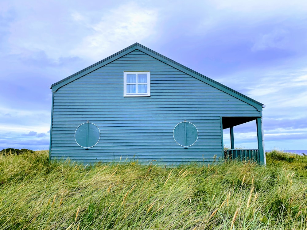 낮에는 흰 구름과 푸른 하늘 아래 푸른 잔디밭에 있는 하얀 목조 주택