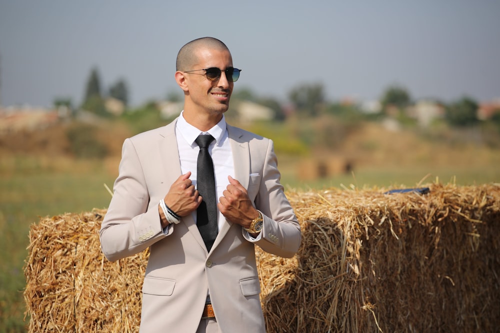 man in brown blazer and black sunglasses standing on brown grass field during daytime