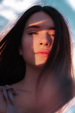 Portrait of a young woman smiling softly with natural light highlighting her features.