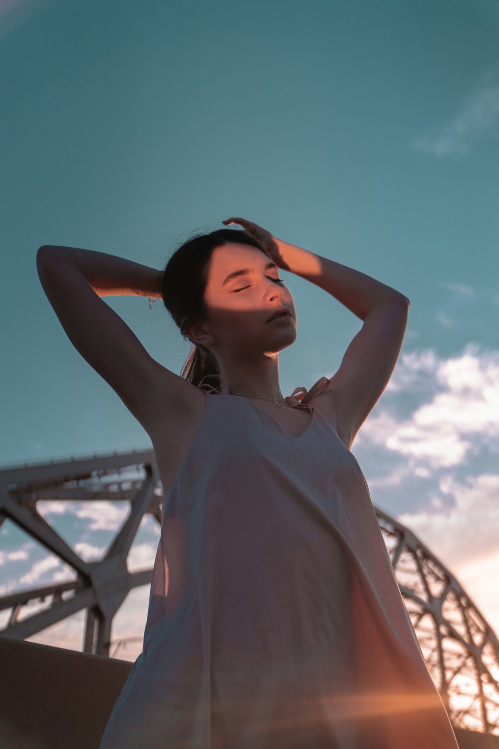 woman in white sleeveless dress standing near bridge during daytime