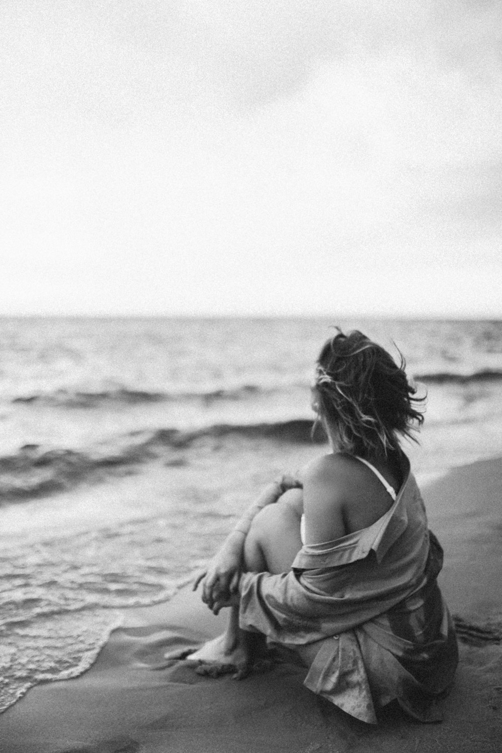 grayscale photo of woman in towel on beach