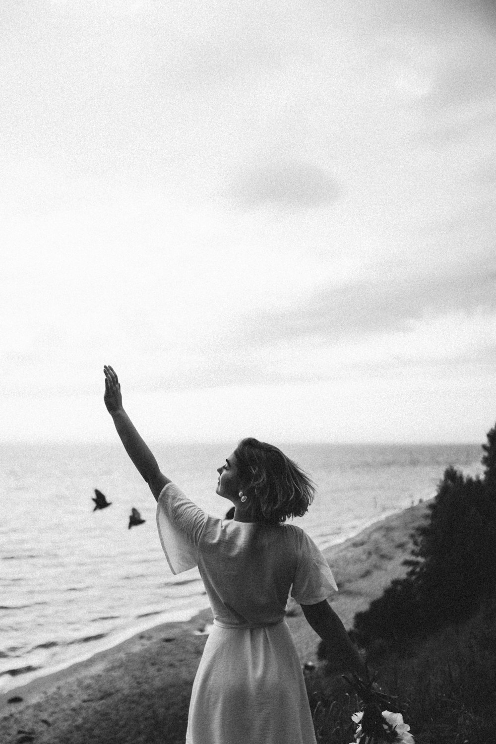 Femme en chemise blanche à manches longues debout sur le bord de mer