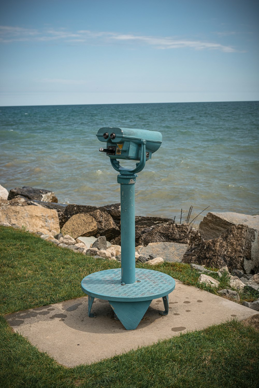 blue and gray binoculars on gray rock near body of water during daytime