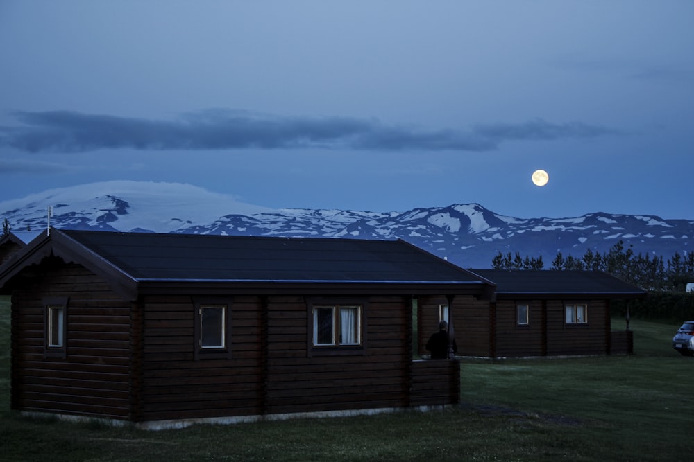 brown wooden house near mountain under full moon