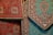 Intricately designed Persian rugs featuring detailed floral and geometric patterns. The rugs predominantly display rich red and teal colors with accents of black and beige. They are layered, showcasing different sections of the designs with ornate borders.