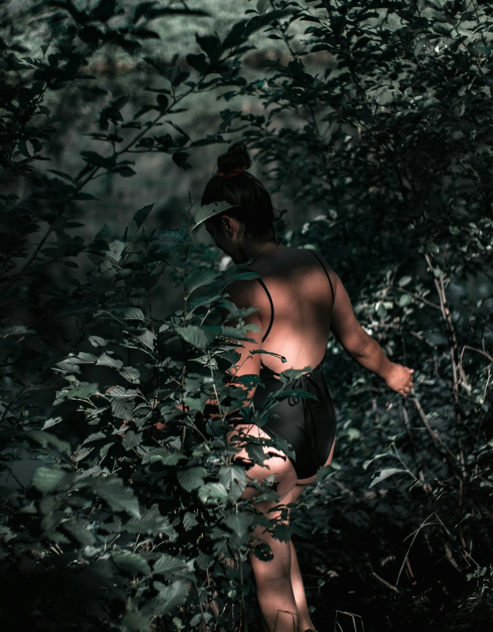 woman in black spaghetti strap top and black hat standing in the middle of forest during