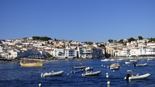 white and blue boat on sea near city buildings during daytime in Cadaqués Spain