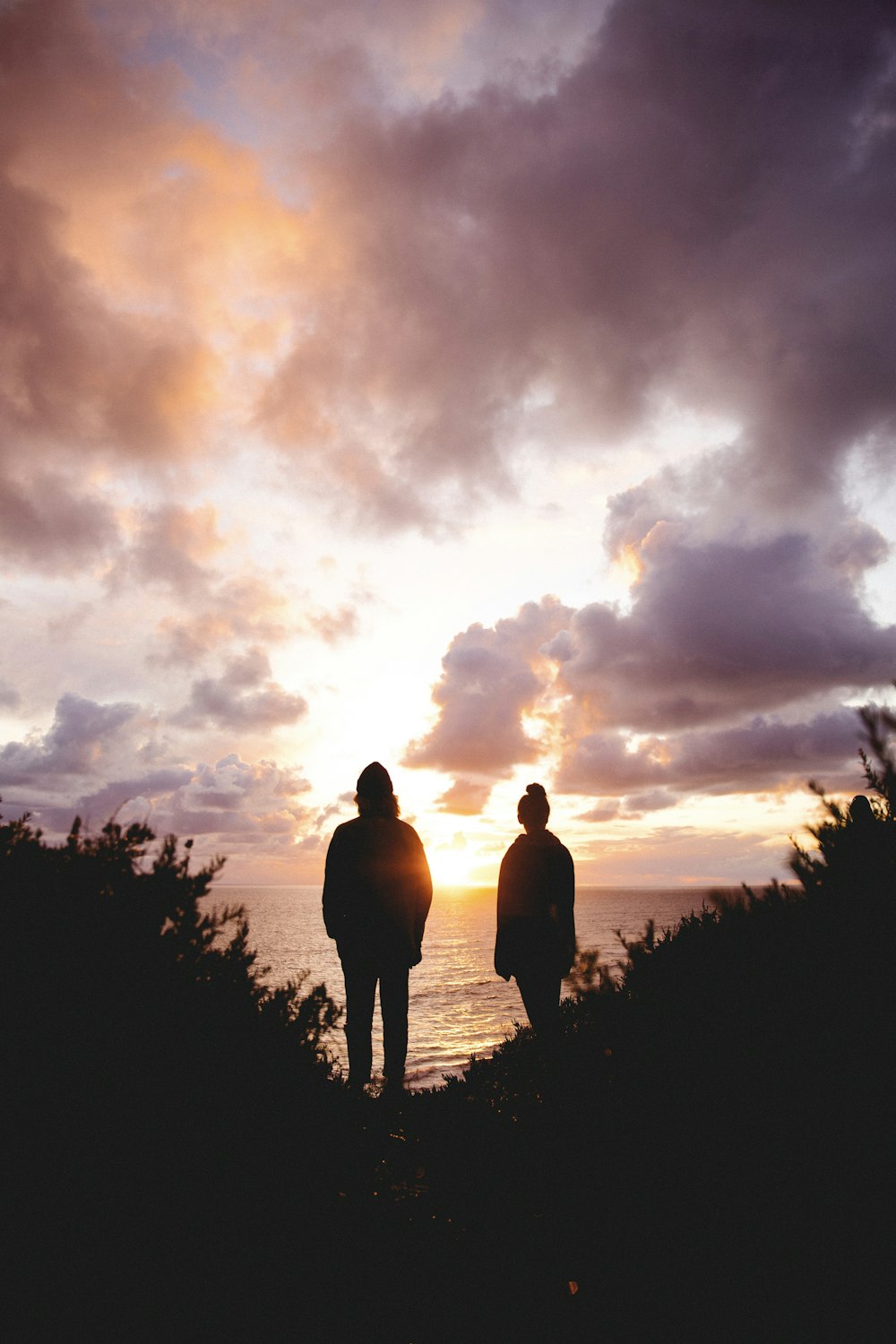 Silhouette von 2 Personen, die bei Sonnenuntergang auf dem Rasen stehen