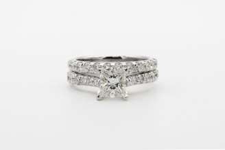 silver diamond studded ring on white surface