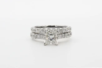 silver diamond studded ring on white surface