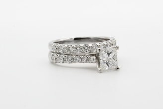 silver diamond ring on white surface