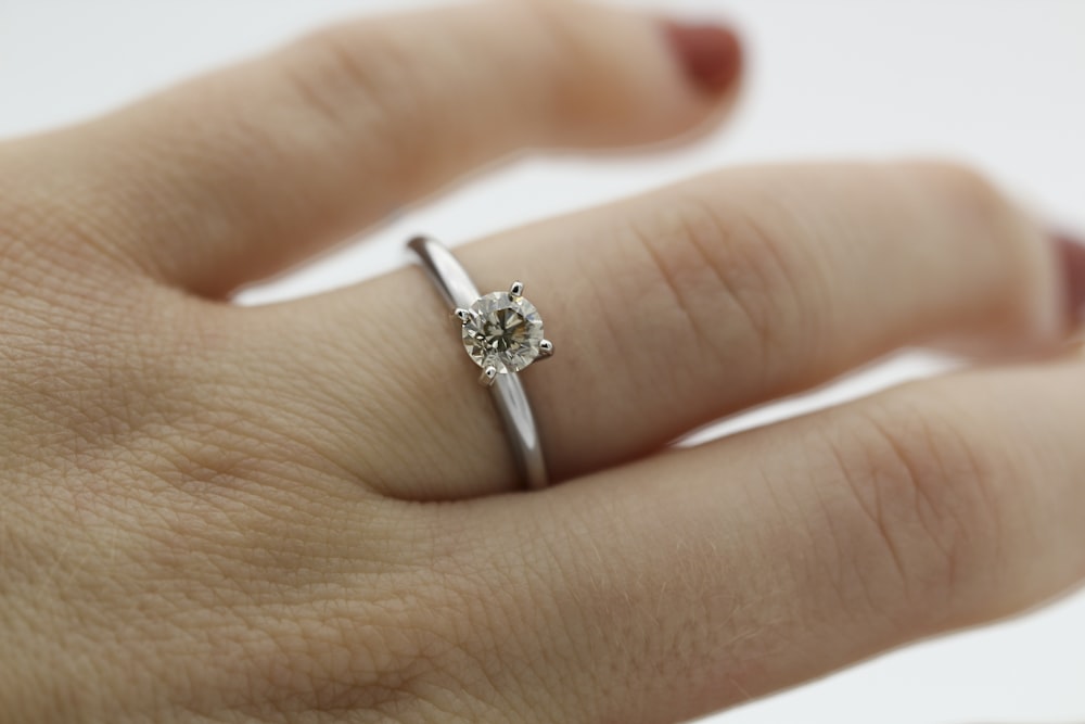 silver diamond ring on persons finger