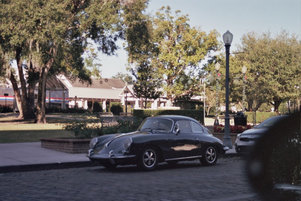 black sedan parked near green trees during daytime