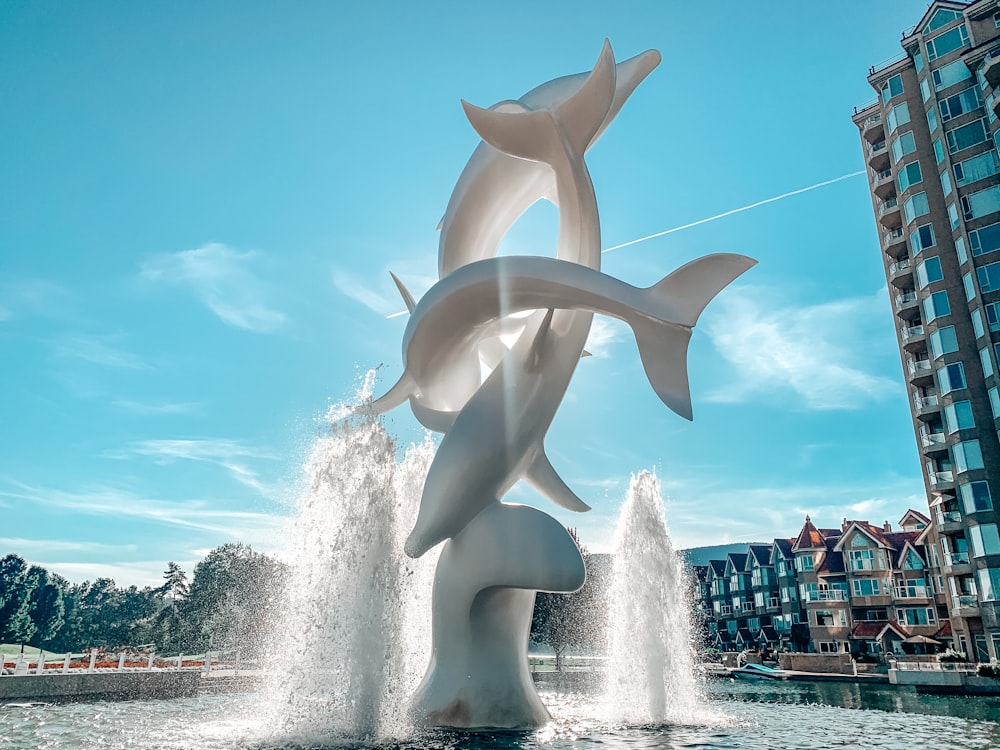 people walking on park with white animal statue under blue sky during daytime