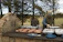 A happy man grilling outdoors with a wooden cutting board beside him.