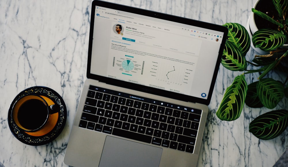 macbook pro beside white ceramic mug