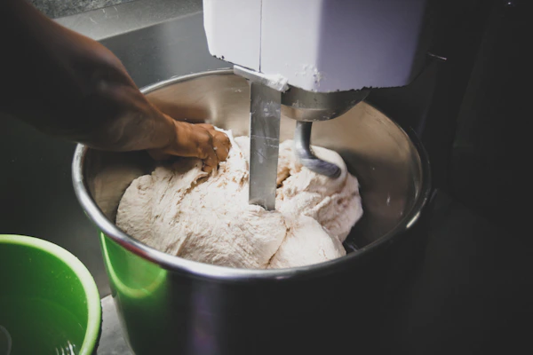 Commercial dough mixers and ovens in a busy restaurant kitchen environment.