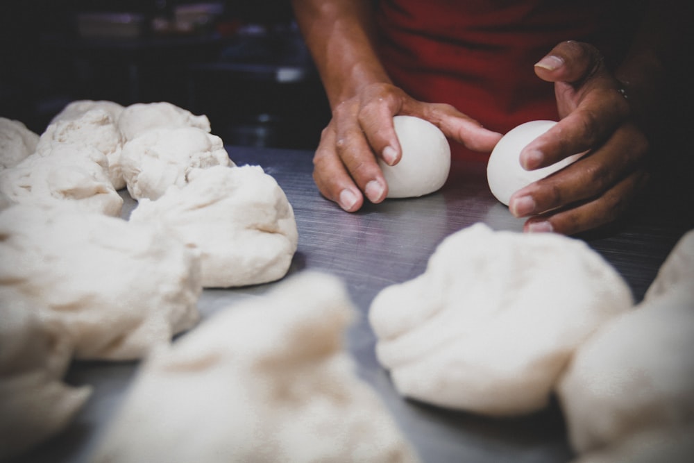 person holding white egg on brown wooden table