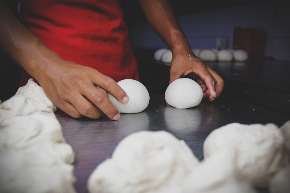 person holding white egg on brown wooden table